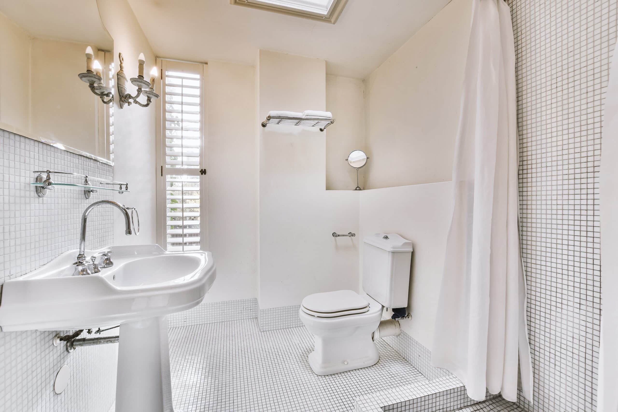 Large modern bathroom with grey marble tiles, a freestanding white tub, frameless glass shower, and a long double vanity overlooking a city skyline.