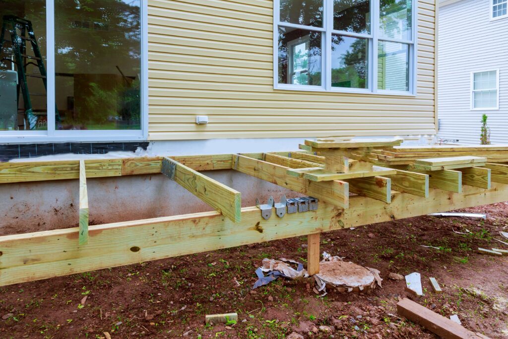 Deck Needs Professional Repair? 5 Signs Before Hurricane Season 2 Professional deck framing installation in Ocala, Florida, featuring pressure-treated wood joists and metal hangers attached to a suburban home exterior.