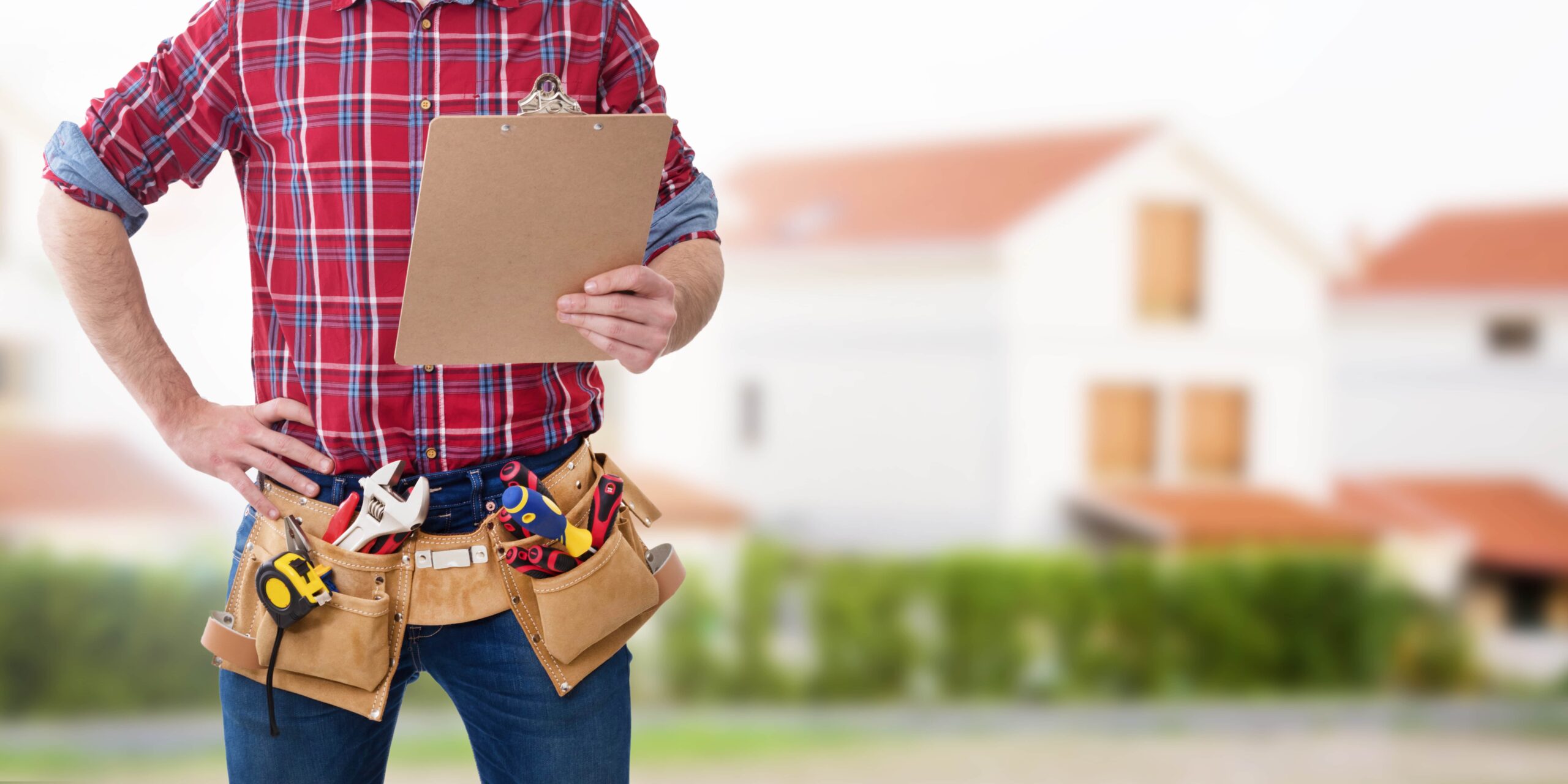 A professional home contractor wearing a tool belt and holding a clipboard, standing in front of a blurred residential house background.