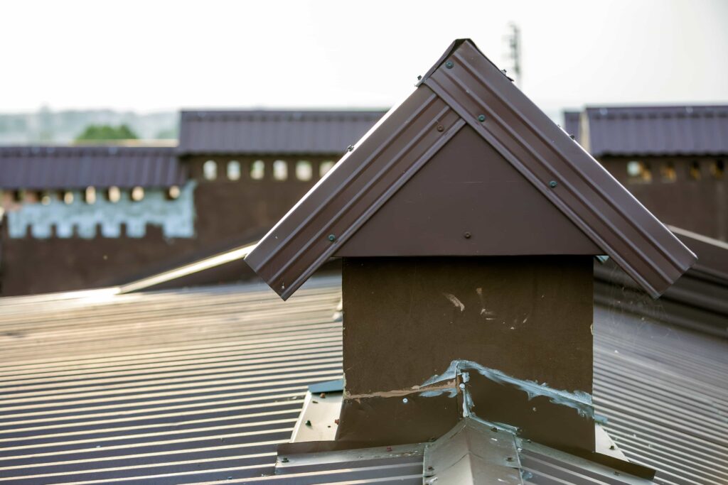 A close-up view of a plastered brown chimney cap and damaged metal roof flashing with failing sealant, highlighting the need for expert chimney flashing repair service in Orlando, Florida.