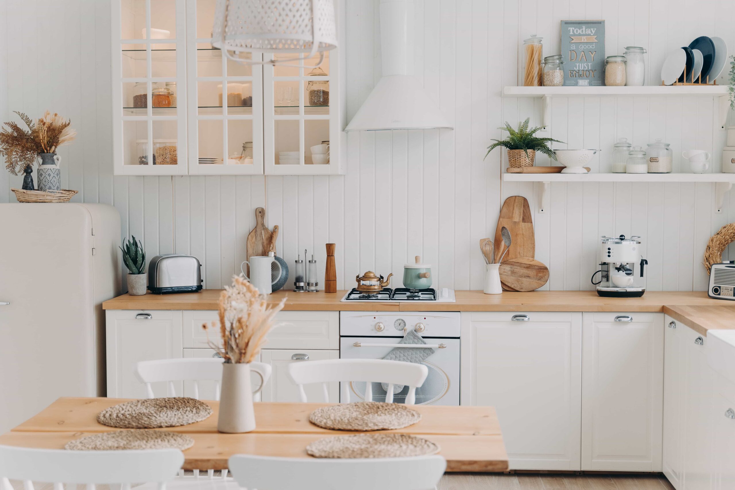 A bright modern farmhouse kitchen featuring white shaker cabinets, natural wood countertops, and open shelving. Professional kitchen remodel service in Orlando, Florida.